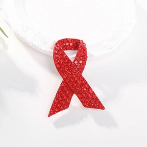 Sparkling red rhinestone ribbon brooch for HIV awareness on white ceramic tray