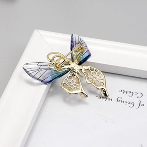 Vue détaillée de la broche papillon en métal doré et ailes dégradées violettes sur support