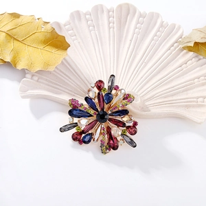 Macro detail of multi-colored rhinestone flower brooch on a white decorative shell tray
