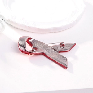 Red ribbon brooch with rhinestones showing the silver alloy back and safety pin