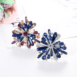 Elegant floral crystal brooch with colorful rhinestones on a white surface with dried flowers