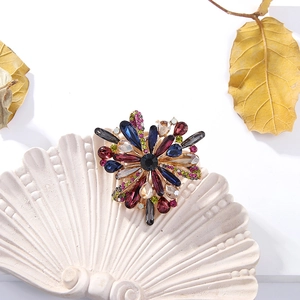 Detail of flower brooch with multicolored crystals on a shell tray and autumn leaf