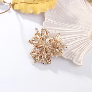 Detailed back view of a gold flower brooch with a secure safety pin on a decorative tray