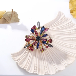 Elegant floral brooch with colorful crystals and gold alloy base on a white shell plate