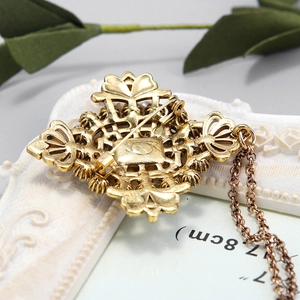 Broche baroque dorée avec motifs solaires et détails de chaîne métallique sophistiqués
