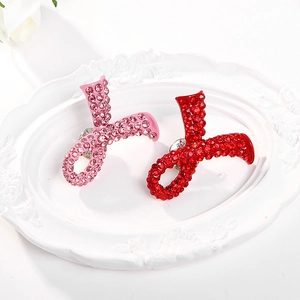 Détail des broches ruban rouges et roses serties de strass brillants dans un plateau blanc