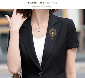 Detail of vintage gold alloy brooch with grey stone and rhinestones on a black blazer
