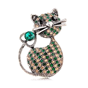Sparkling cat brooch with green crystals and vintage silver finish on white background