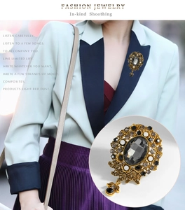 Detail of vintage gold brooch with grey crystal and leaf carvings on model's coat