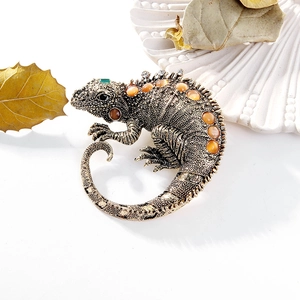 Vintage lizard brooch with bronze finish and orange gemstone on an autumn leaf background