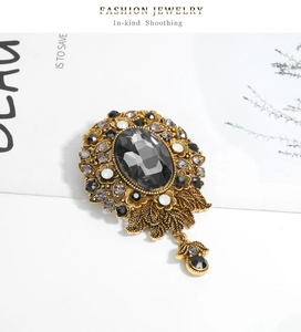 Macro detail of Victorian-style brooch with dark gray crystal and golden metal filigree