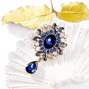 Détail d'une broche vintage avec cristal bleu foncé et motif filigrane doré ciselé
