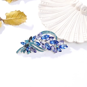 Elegant silver leaf brooch featuring blue marquise crystals on a white textured tray