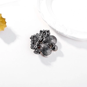 Black crystal brooch with floral design and secure pin clasp on textured base