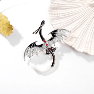 Détail d'une broche dragon argentée avec gemmes rouges et émail blanc sur fond stylisé