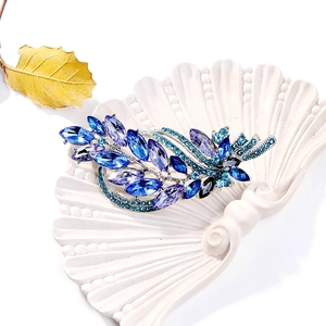 Macro detail of vintage leaf brooch with blue and purple marquise crystals on silver base