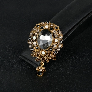 Vintage gold brooch with grey crystal and black pendant on a professional jewelry display