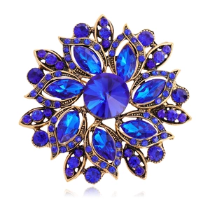 Detailed close-up of a vintage floral brooch with deep blue crystals and bronze base
