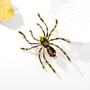 Detail of vintage spider brooch with yellow-green striped legs and emerald rhinestones