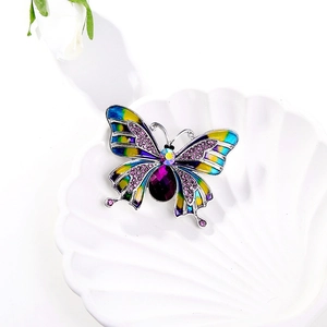 Vintage enamel butterfly brooch with purple crystals on a decorative white shell tray