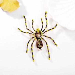 Macro detail of vintage spider brooch featuring green crystals and enamel legs on shell tray