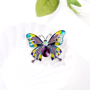 Macro detail of enamel butterfly brooch with purple gemstone and crystals on silver base