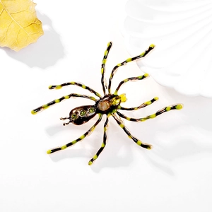 Macro view of vintage spider brooch with green stripes and crystal inlays on white background