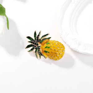 Broche ananas créative avec émail jaune et feuilles vertes sur un fond blanc épuré