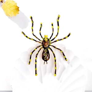Detailed view of vintage spider brooch with green crystals and enamel on a white shell