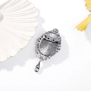 Back view of a vintage silver-plated oval brooch with a teardrop pendant and crystal details