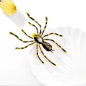 Macro shot of spider brooch with green gemstone on shell tray with autumn leaf
