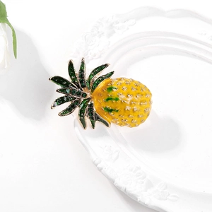 Vue détaillée de la broche ananas en émail avec strass verts sur socle doré élégant