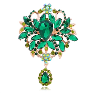 Macro shot of vintage gold brooch with teardrop emerald crystals and rhinestone details