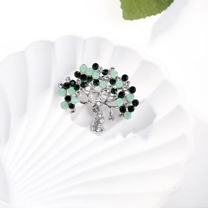 Elegant Tree of Life brooch with green crystals on a white shell plate display