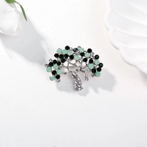 Elegant silver tree of life brooch with green crystals and rhinestones on white decor