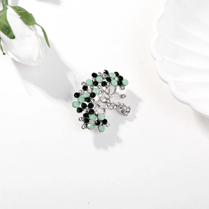 Detailed view of silver tree brooch with green rhinestones and clear crystals decoration