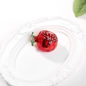 Detail of red enamel pomegranate brooch with green leaves and sparkling rhinestones