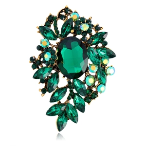 Macro shot of vintage floral glass brooch with green gems and golden metal detail