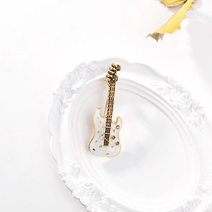 Détail d'une broche guitare avec paillettes colorées et strass sur plateau blanc