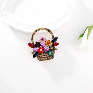 Elegant gold flower basket brooch with colorful rhinestones on a white background