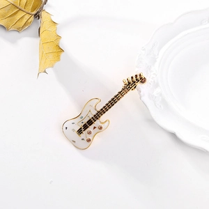 Détail d'une broche guitare vintage avec émail blanc et finition dorée sur céramique