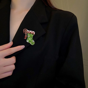 Elegant Christmas stocking brooch with green enamel and rhinestones on black suit