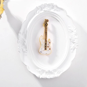 Détail d'une broche guitare avec incrustation en nacre et cristaux roses en cadre