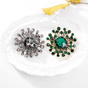 Detailed close-up of crystal cluster brooches in emerald green and smoky gray shades