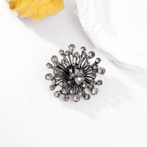 Macro shot of radial crystal brooch with dark square center stone on white background