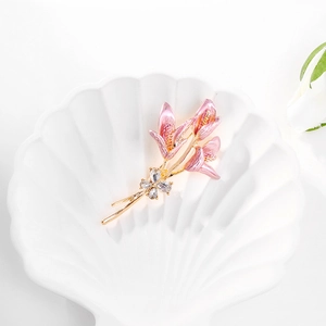 Broche fleur de lys dorée avec émail rose et strass sur un plateau en céramique blanche