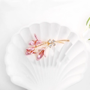 Vue détaillée d'une broche lys doré avec pétales en émail rose et cristaux de zircone
