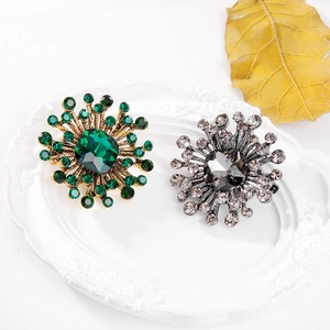 Detailed close-up of crystal sunflower brooches on white plate with fall leaves