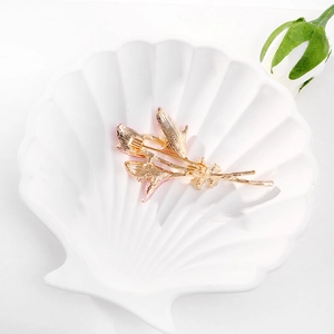 Broche élégante en forme de lys doré avec émail rose sur un plateau décoratif