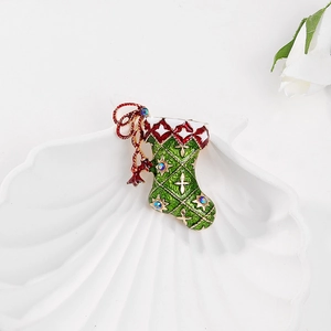 Macro detail of enamel Christmas stocking brooch with green lattice and red bow